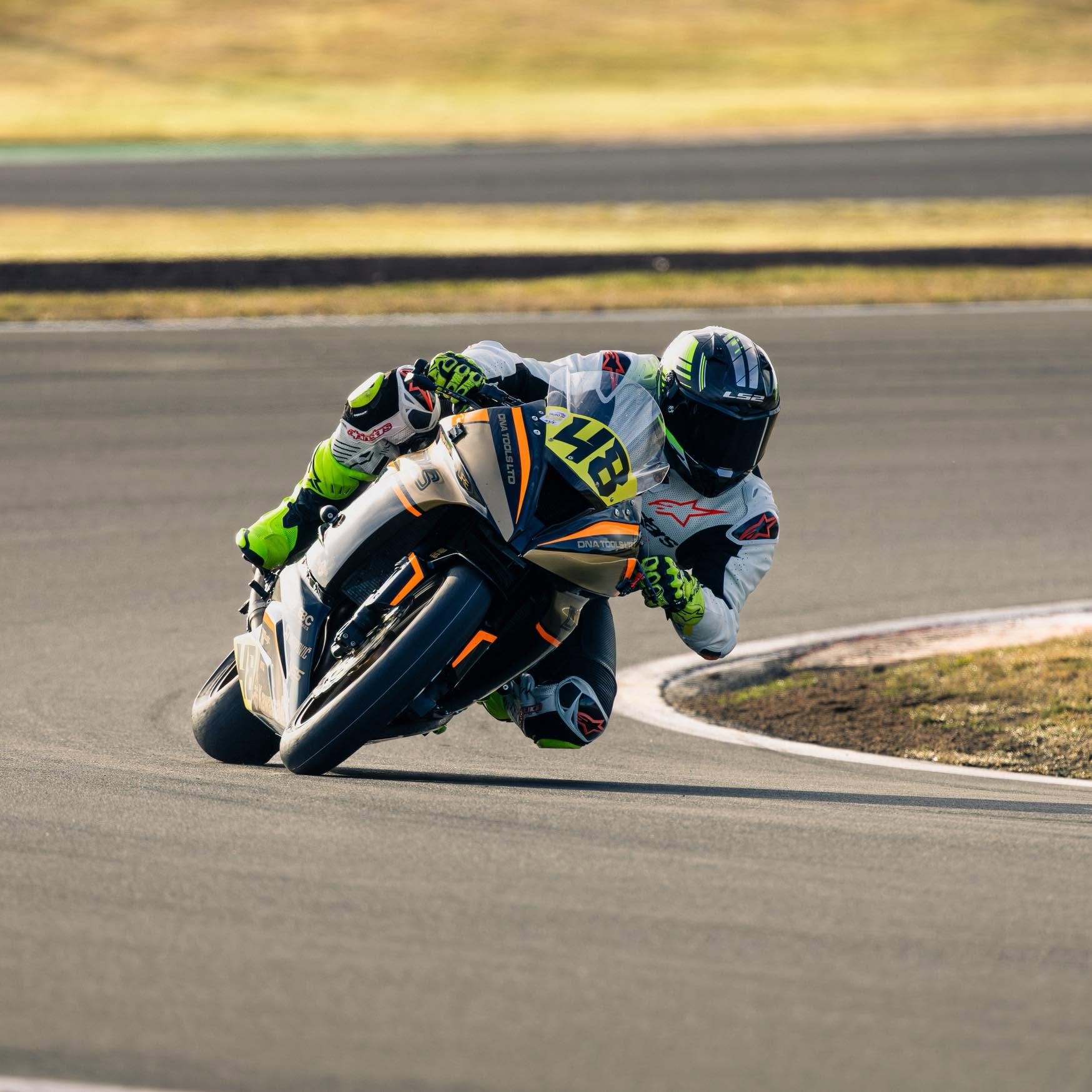 The owner's number 48 superbike in DNA Tools livery, knee down through a corner on track.